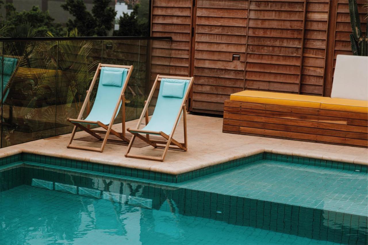 The Click Clack Hotel Medellín Eksteriør billede A pair of deck chairs by a pool